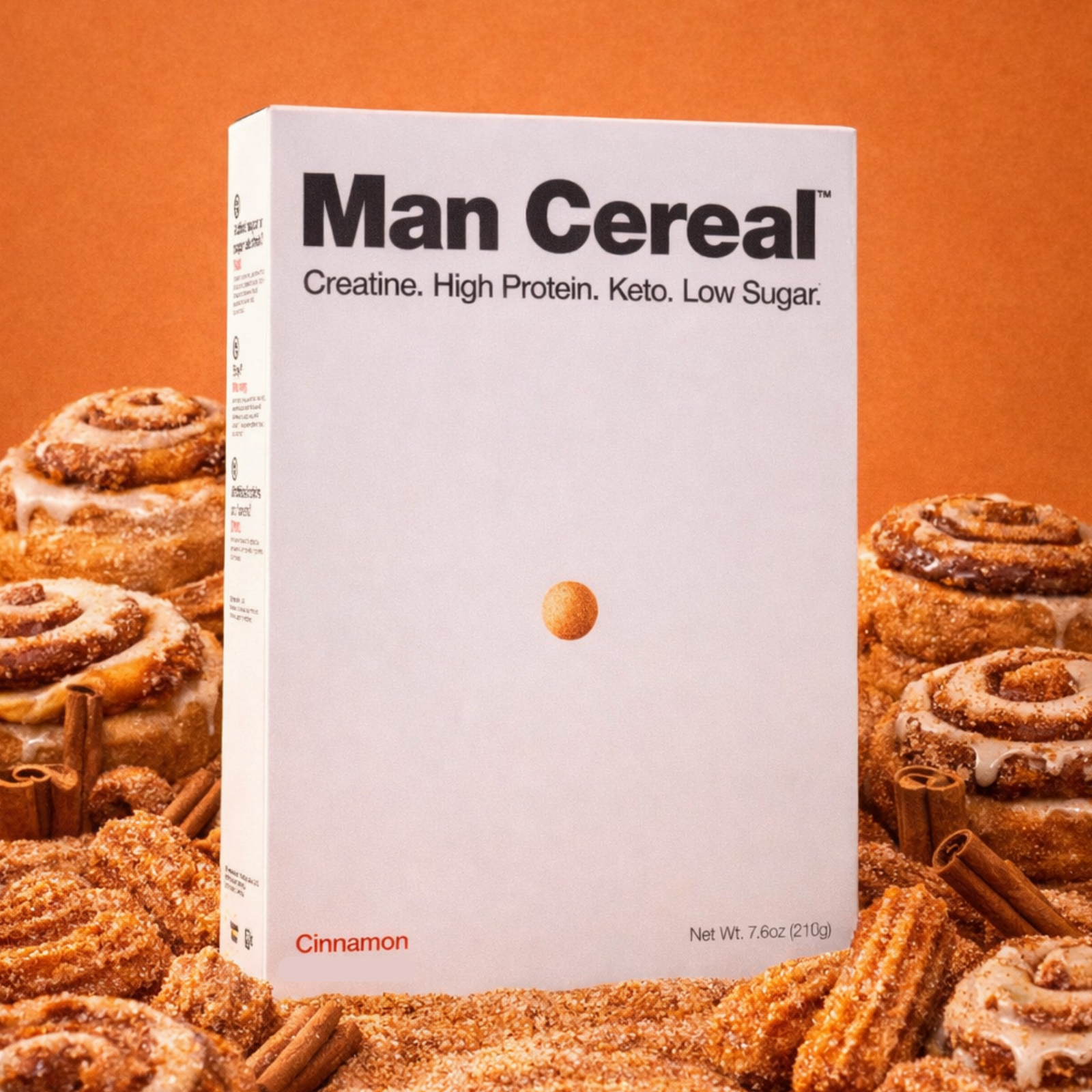 Box of 'Man Cereal' surrounded by cinnamon rolls on an orange background